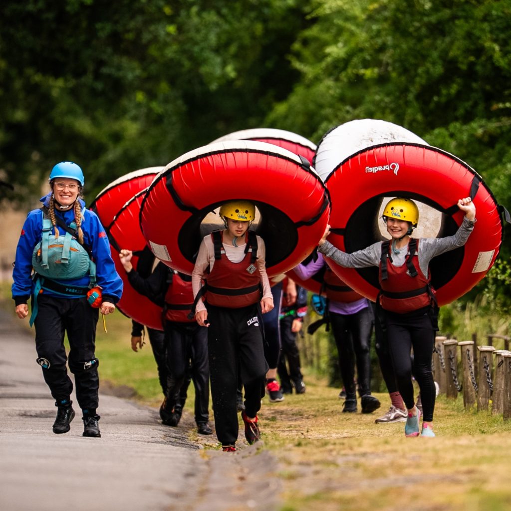 People carrying inflatable water sport equipment