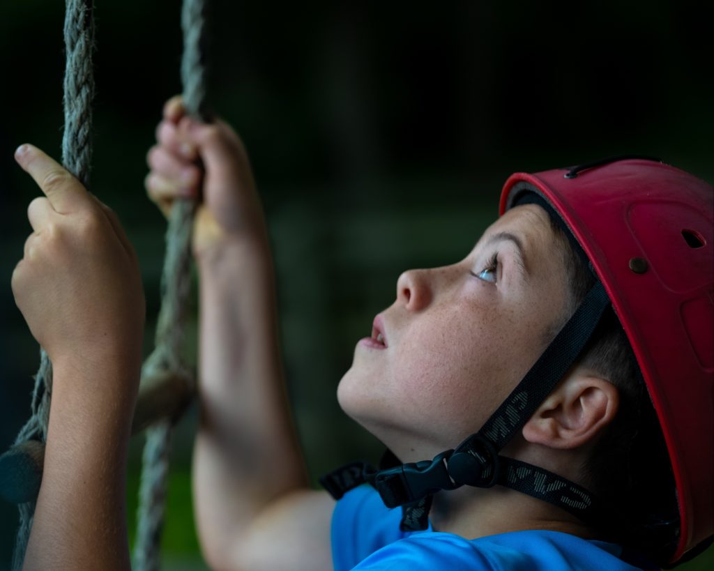 Boy in hard hat holding ropes, looking up